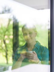 Image showing young woman drinking morning coffee by the window