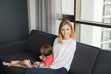 Image showing mother and her cute little daughter are using a tablet