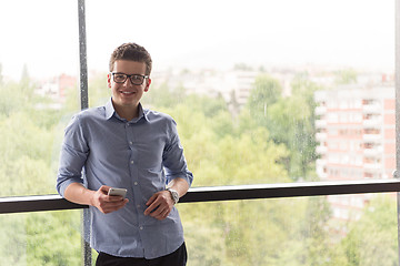 Image showing Businessman Standing In A Modern Building Near The Window With P