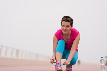 Image showing Young woman tying shoelaces on sneakers