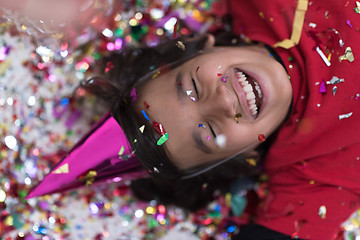 Image showing kid blowing confetti while lying on the floor