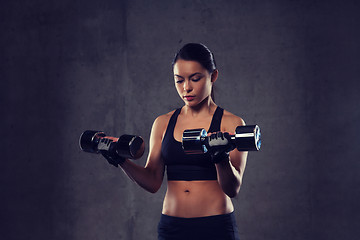 Image showing young woman flexing muscles with dumbbells in gym