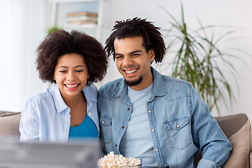 Image showing smiling couple with popcorn watching tv at home