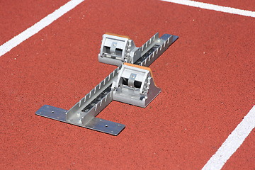 Image showing Athletics starting blocks on race red track