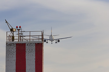 Image showing Airplane landing to the airport over the building with lights