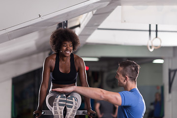 Image showing black woman doing parallel bars Exercise with trainer