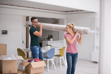 Image showing couple carrying a carpet moving in to new home