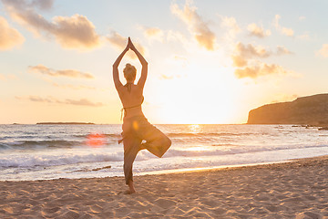 Image showing Woman practicing yoga on sea beach at sunset.