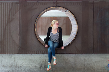 Image showing Young thoughtful woman relaxing on bench in city park.