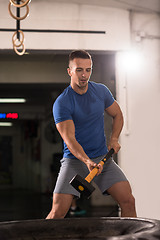 Image showing man workout with hammer and tractor tire