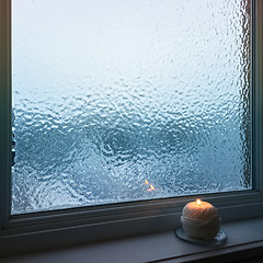 Image showing Blue frosted window and cozy candlelight