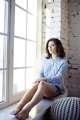 Image showing young pretty brunette woman in her bedroom sitting at window, happy smiling lifestyle people concept 