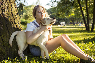 Image showing young attractive blond woman playing with her dog in green park at summer, lifestyle people concept