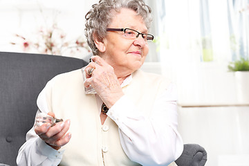 Image showing Mature well groomed woman perfumes to expensive perfumes. Mature well groomed woman with perfume bottle, smelling perfume.