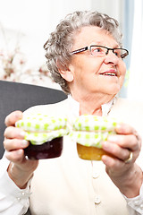 Image showing A gift from her grandmother, colorful jam. Mature woman with personally prepared jars of jams. 