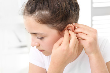 Image showing A child with a hearing aid. The girl assumes hearing aid. Hearing aid for your child 