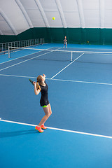 Image showing The young girl in a closed tennis court with ball