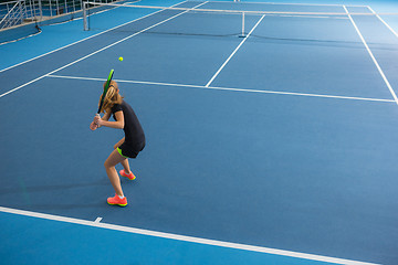 Image showing The young girl in a closed tennis court with ball