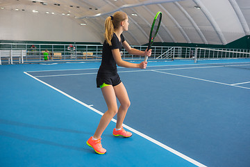 Image showing The young girl in a closed tennis court with ball