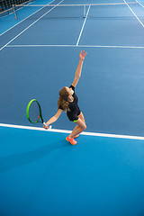 Image showing The young girl in a closed tennis court with ball