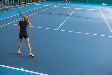 Image showing The young girl in a closed tennis court with ball