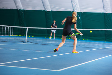 Image showing The young girl in a closed tennis court with ball