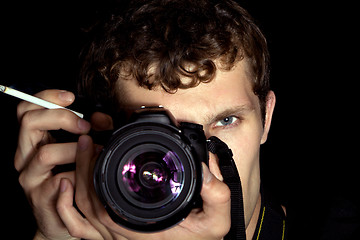Image showing The young man - photographer behind work. Isolated on a black ba