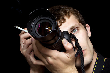 Image showing The young man - photographer behind work. Isolated on a black ba