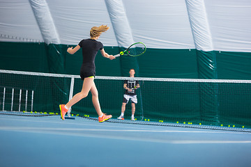 Image showing The young girl in a closed tennis court with ball