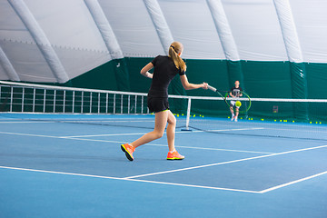 Image showing The young girl in a closed tennis court with ball