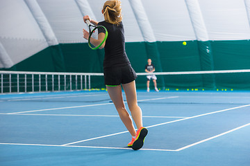 Image showing The young girl in a closed tennis court with ball