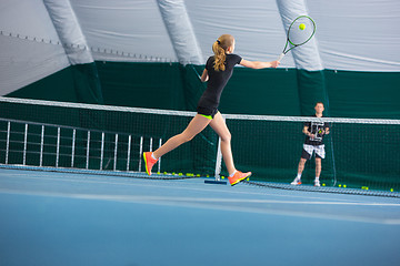 Image showing The young girl in a closed tennis court with ball