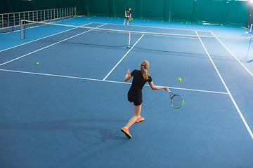 Image showing The young girl in a closed tennis court with ball