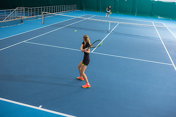 Image showing The young girl in a closed tennis court with ball