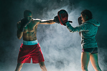 Image showing Handsome Afro American boxer with bare torso is practicing punches with a partner at the fight club