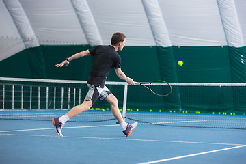 Image showing The young man in a closed tennis court with ball