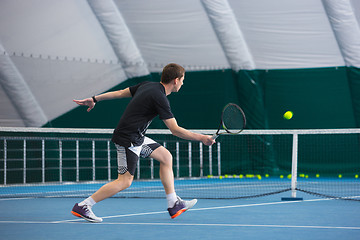 Image showing The young man in a closed tennis court with ball