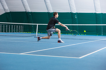 Image showing The young man in a closed tennis court with ball