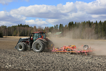 Image showing Farm Tractor and Cultivator on Field at Spring