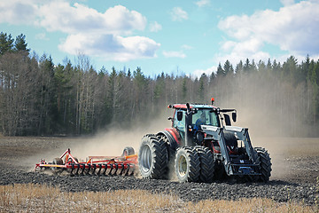 Image showing Farm Tractor and Cultivator on Field at Spring