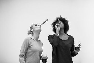 Image showing smiling women in party caps blowing to whistles