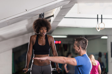 Image showing black woman doing parallel bars Exercise with trainer