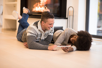 Image showing multiethnic couple using tablet computer on the floor