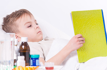 Image showing Sick boy in bed reading book