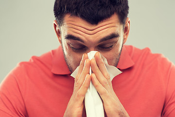 Image showing sick man blowing nose to paper napkin at home