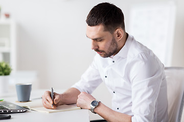 Image showing businessman writing to notebook at office