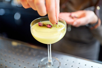 Image showing bartender decorating cocktail in glass at bar