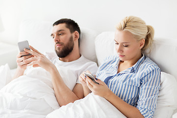 Image showing couple with smartphones in bed at home