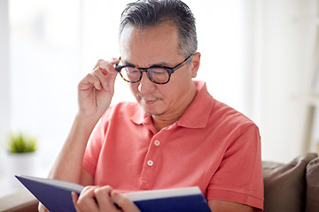 Image showing man in glasses reading book at home