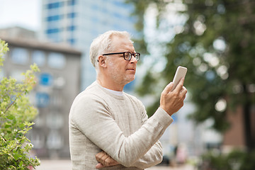 Image showing senior man texting message on smartphone in city